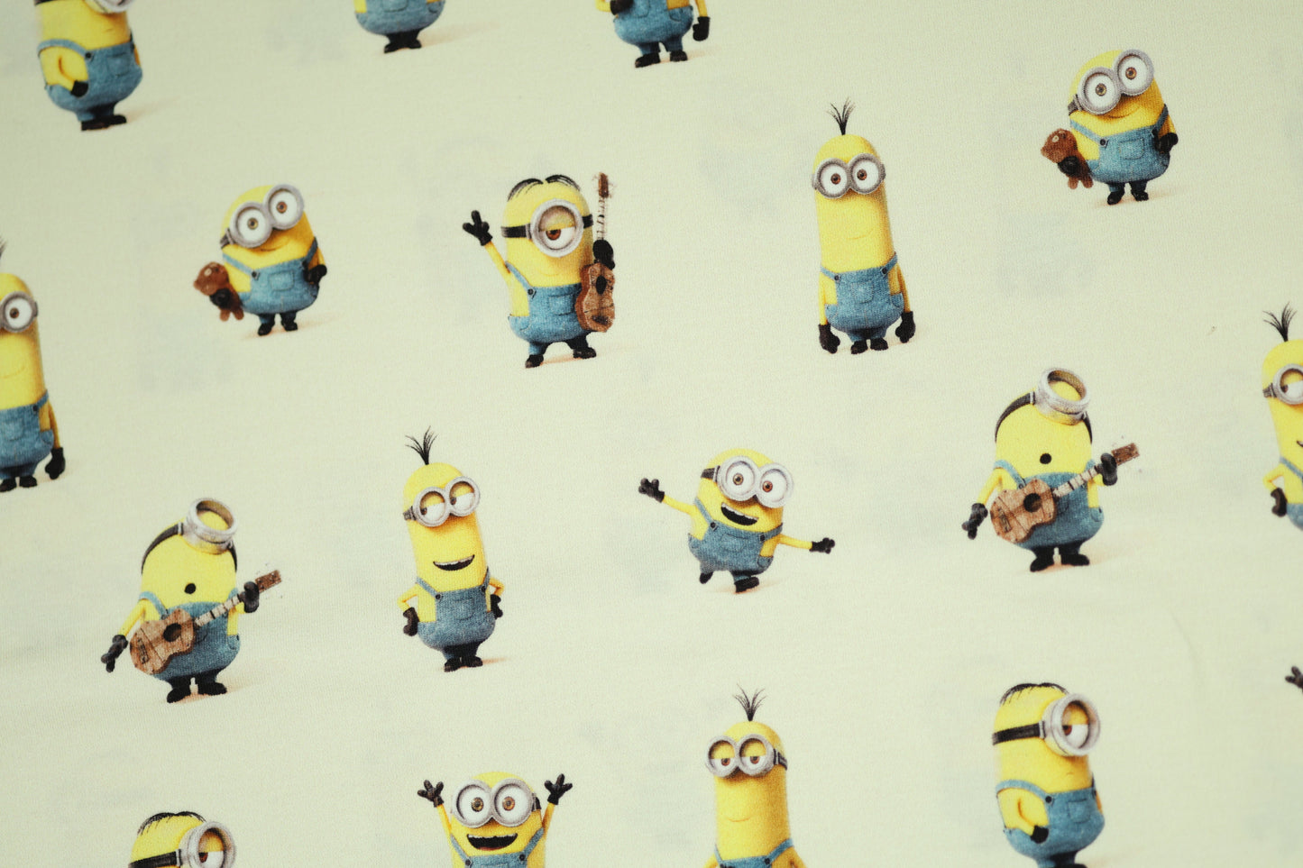 Lustiger Baumwollstoff mit Minions auf cremefarbenem Hintergrund.