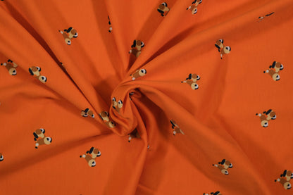Oranger Baumwolljersey mit kleinen Hundemotiven – Detailaufnahme der Stoffstruktur
