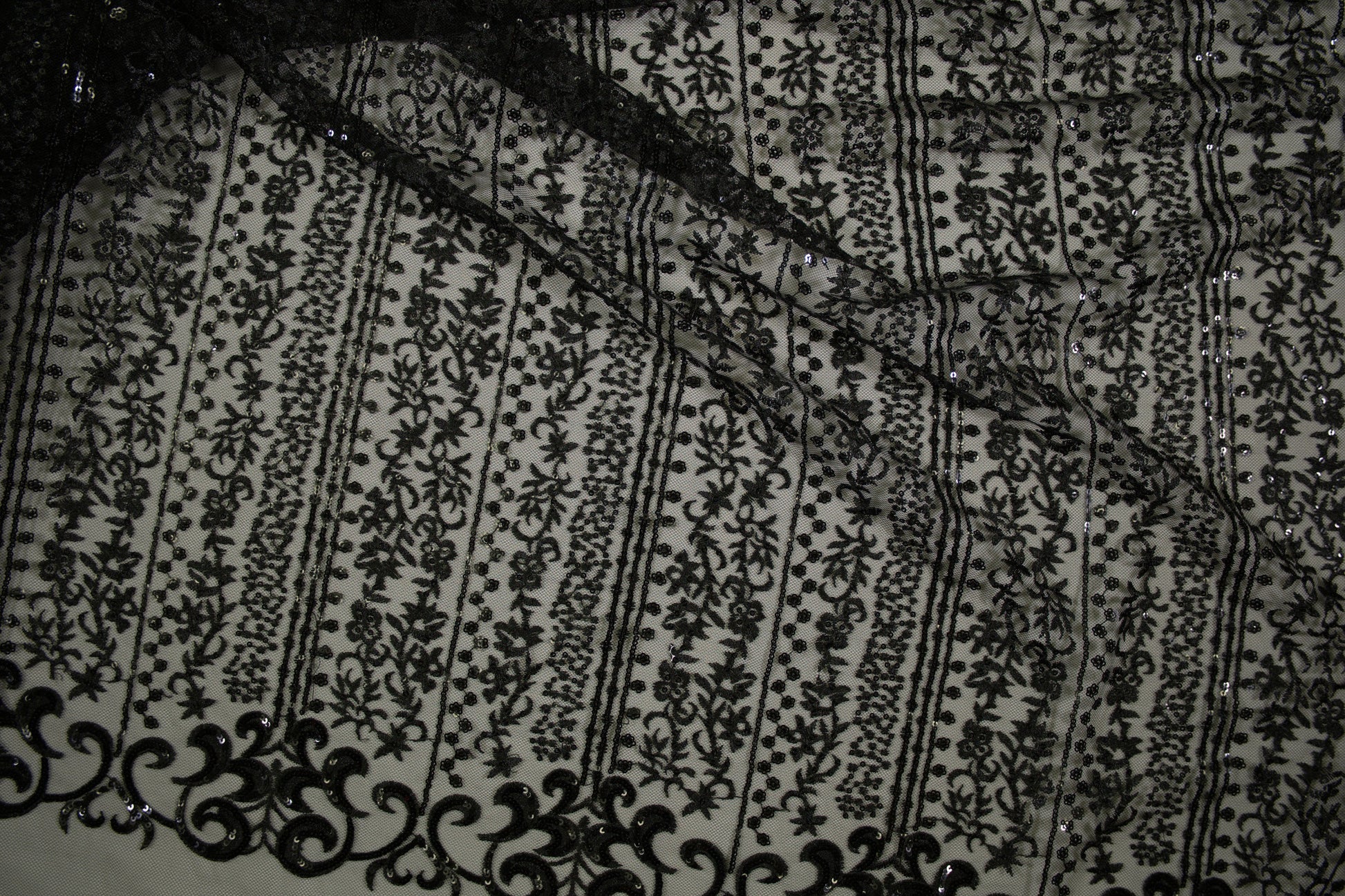 Schwarze Spitzenware auf Tüll mit floralen Streifen und Pailletten in Nahaufnahme