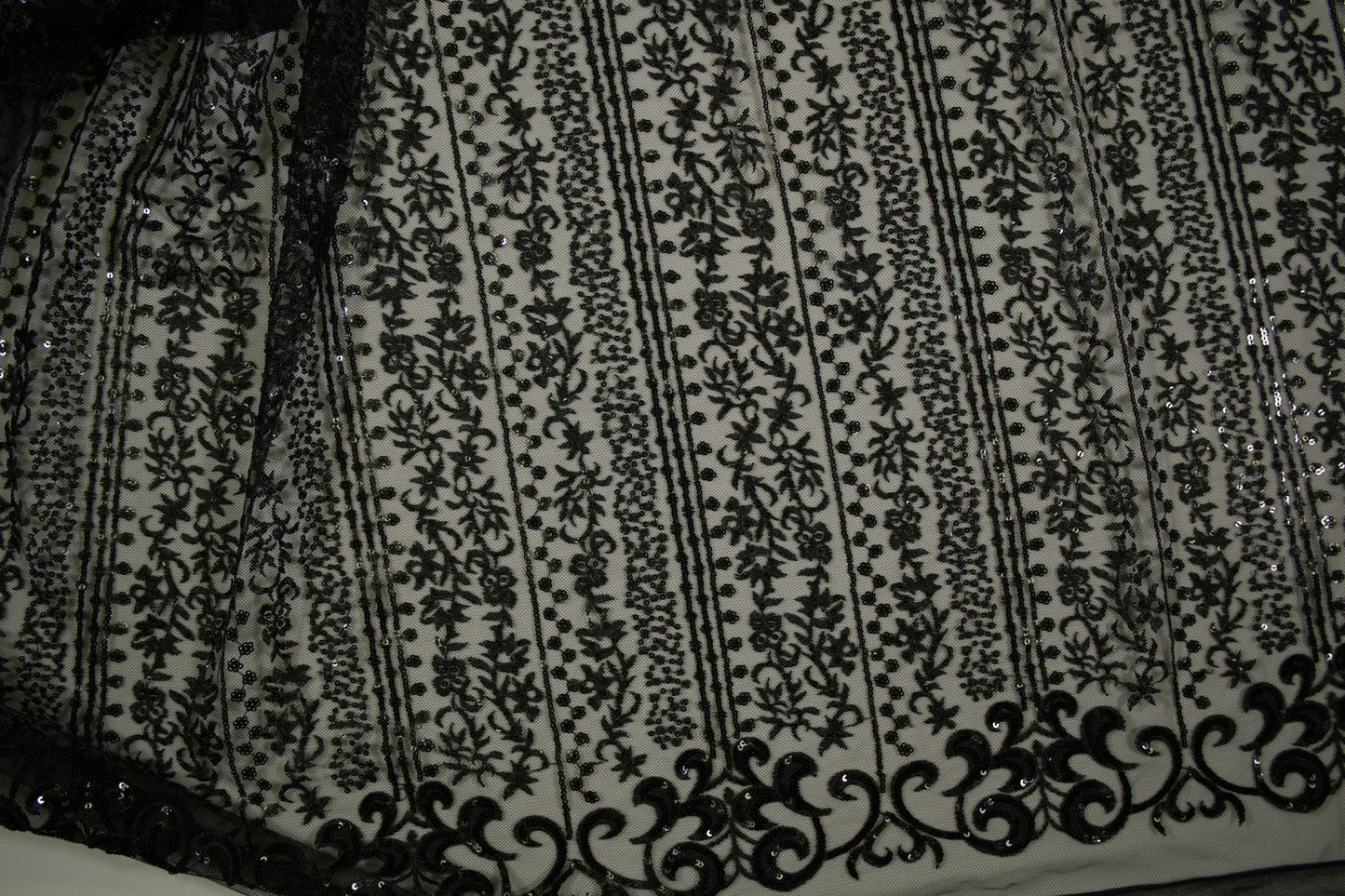 Schwarze Spitzenware auf Tüll mit floralen Streifen und Pailletten in Nahaufnahme