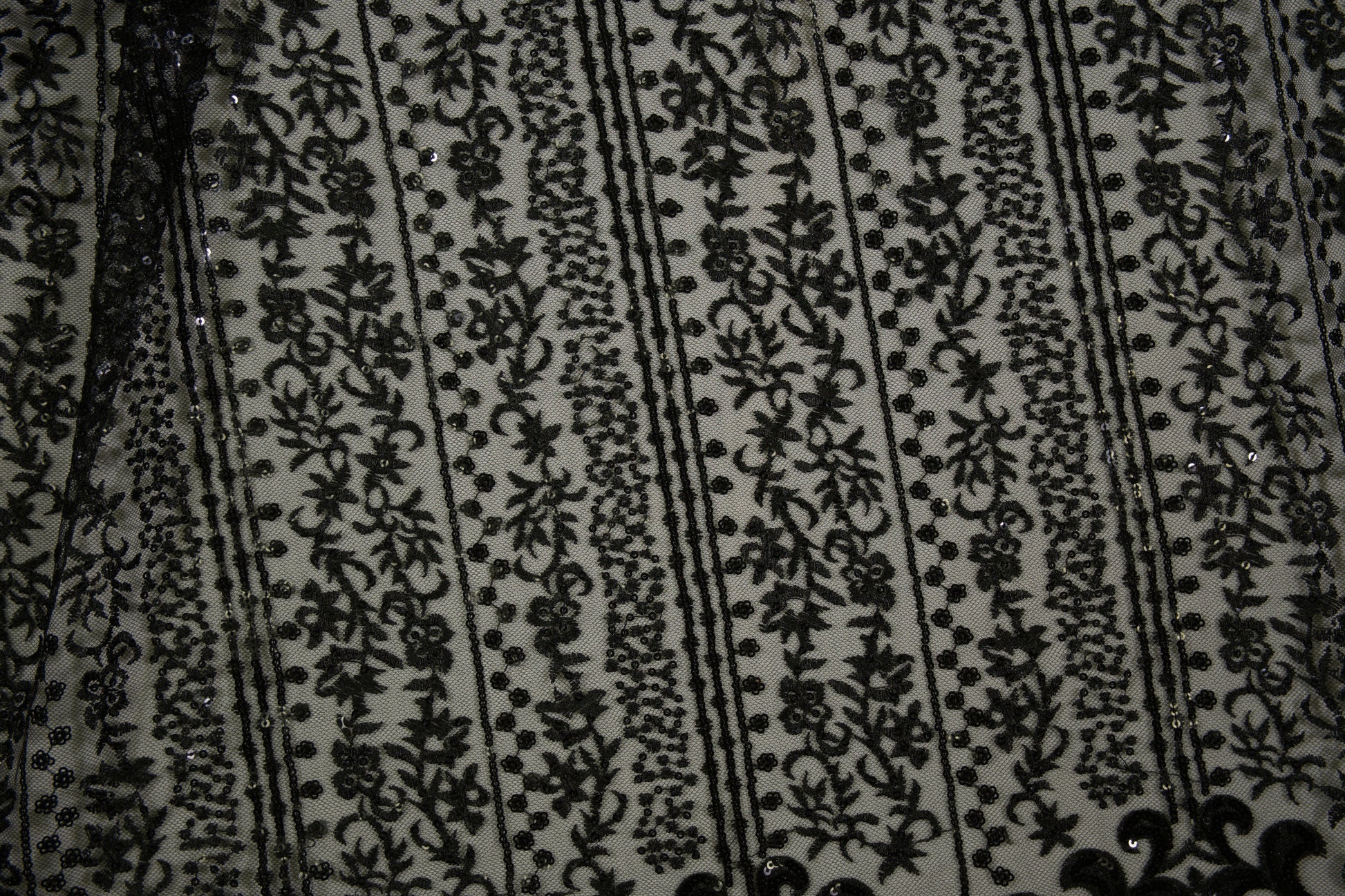 Schwarze Spitzenware auf Tüll mit floralen Streifen und Pailletten in Nahaufnahme