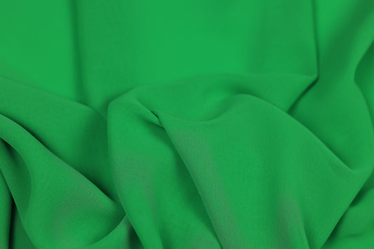Grüner fließender Chiffonstoff mit elegantem Faltenwurf – ideal für Kleider und Blusen