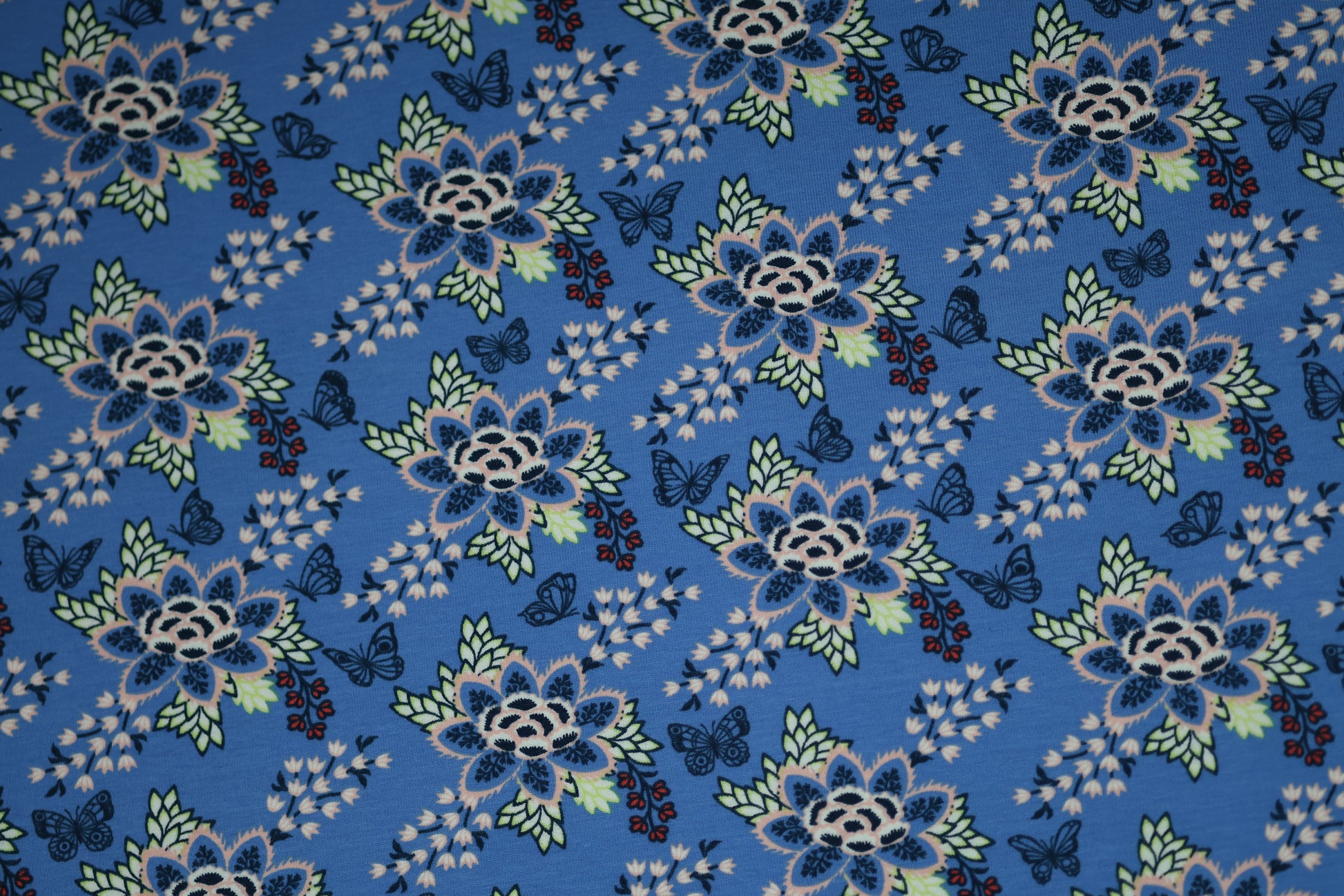 Blauer Baumwollstoff mit floralen Ornamenten und Schmetterlingen.